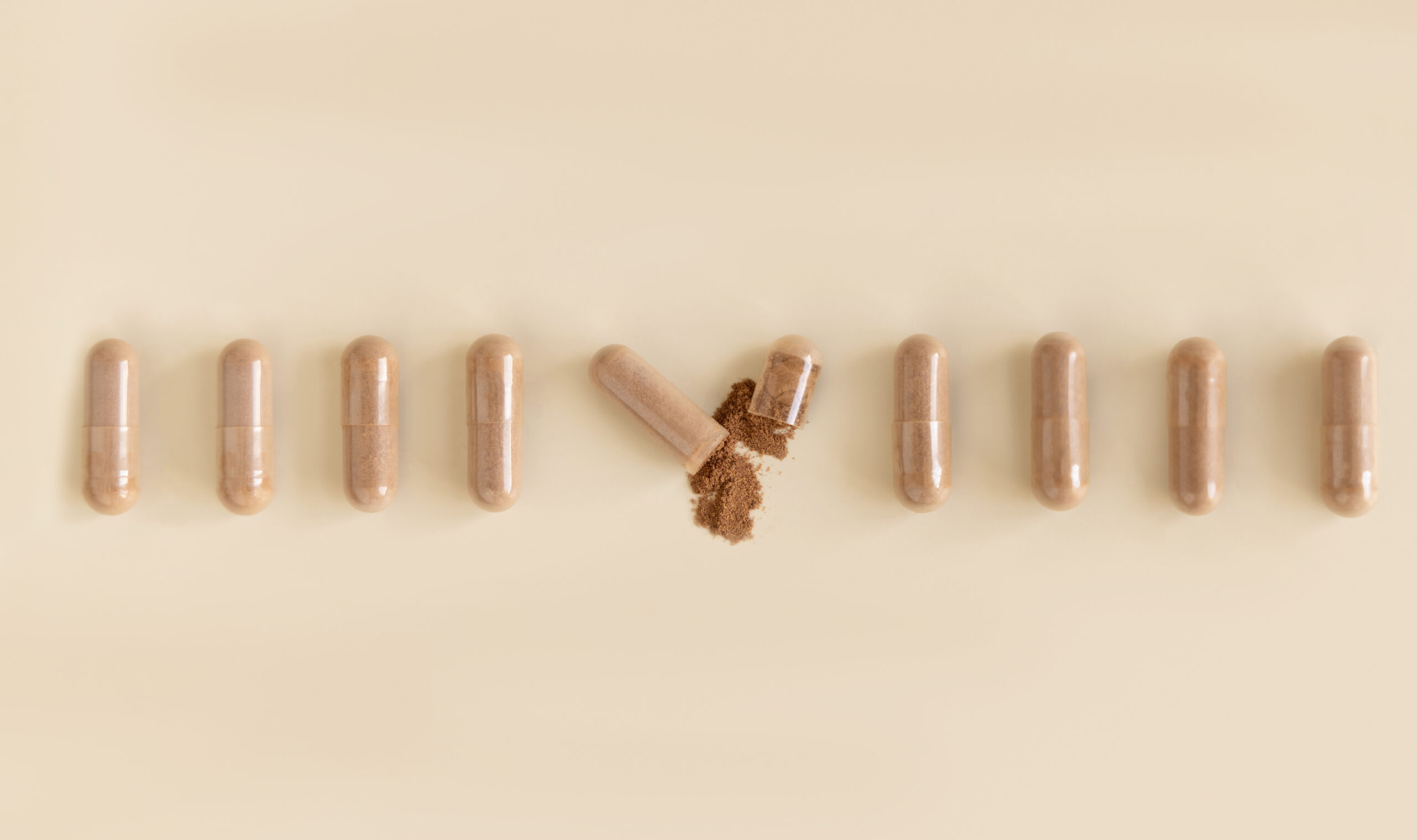 Brown supplements in a row on a beige surface