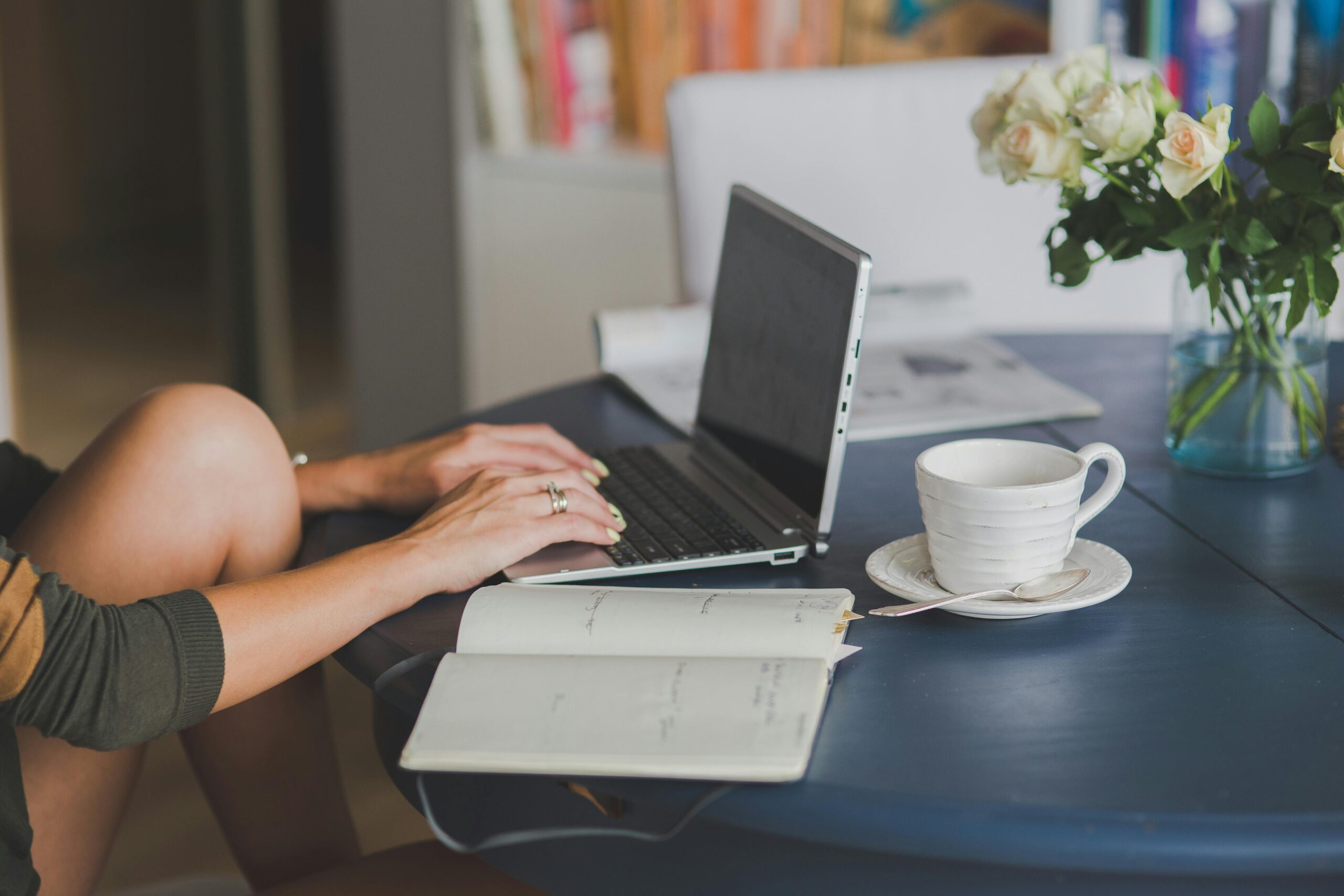 woman working on a laptop with a coffee and notebook on the desk